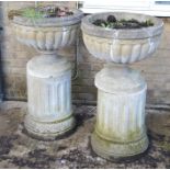 A pair of large garden urns, raised on fluted columns, 99cm high.