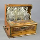 An oak tantalus, with three cut glass decanters and mirrored back, and drawer to the front.