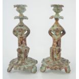 A pair of painted metal candlesticks in the form of cherubs.