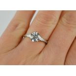 A platinum diamond solitaire ring with brilliant cut diamond flanked by baguette cut diamonds to the