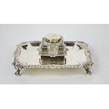 A silver desk stand of shaped wavey edged border, with pierced decoration and raised on four