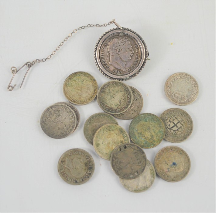 A group of silver threepenny coins together with a George III coin brooch