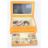 A wooden jewelry box containing a selection of vintage costume jewelry to include, earrings,