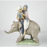 A Lladro porcelain figure group; two Hindu children riding an elephant, numbered 5352, 24cm high.