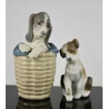 A Lladro porcelain puppy in a basket, and another with a snail on his paw.