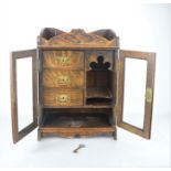 An oak smokers cabinet with three interior drawers with original key and glass fronted doors