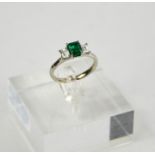 A platinum, emerald (0.83ct), and diamond (0.58ct total) three stone ring in platinum, size N½,