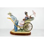 A large Lladro porcelain figure group titled The Rickshaw Ride, no. 1383, raised on a wooden base,