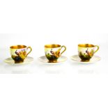 A set of three Royal Worcester porcelain cabinet cups and saucers, painted with peacocks in