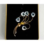 A yellow metal and pale blue topaz floral spray brooch.