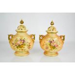 A pair of Royal Worcester peach and ivory ground bulbous vase and covers painted with flowers with