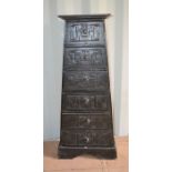 A pyramid shaped chest of six graduated drawers carved with tribal figures