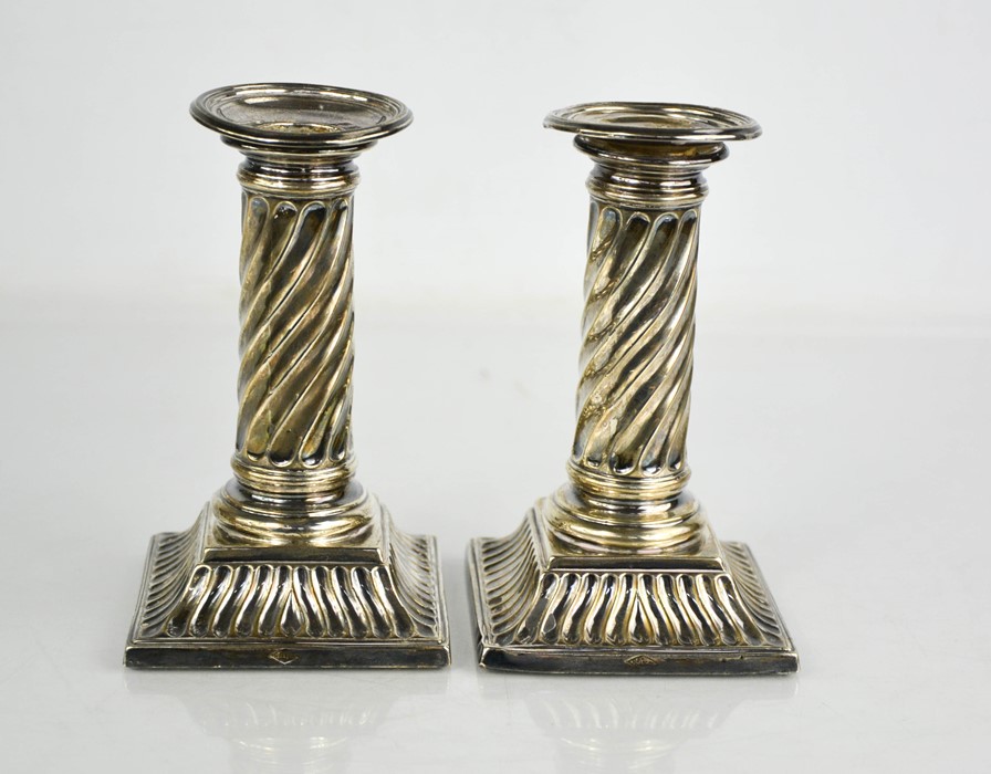 A pair of silver candlesticks with fluted columns.