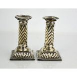 A pair of silver candlesticks with fluted columns.