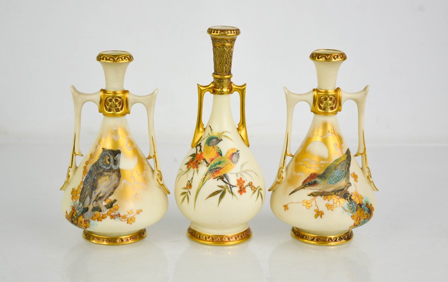 A garniture of three Royal Worcester twin handled vases, of Persian design, painted with birds on an