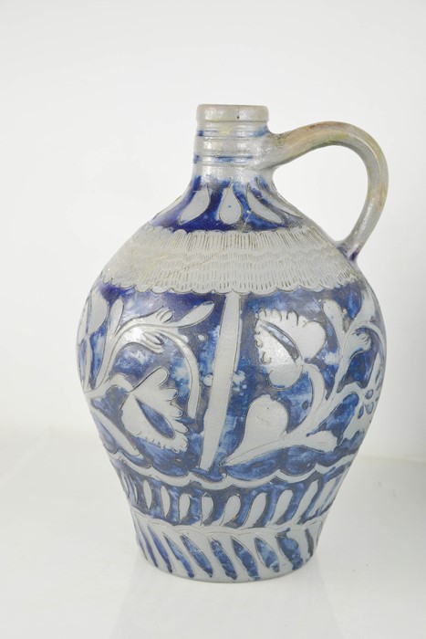 A stoneware blue and grey bellarmine jug, embossed with stylised flowers. A/F