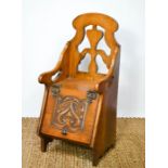 An Arts & Crafts oak child's box chair, with pierced back and carved lid.