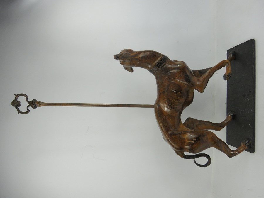 A metal doorstop in the form of a greyhound with light brown patination