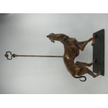 A metal doorstop in the form of a greyhound with light brown patination