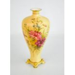 A Royal Worcester blush ivory slender vase, painted with flowers, raised on four gilded feet,