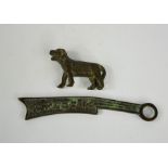 A small bronze tiger, and a Chinese bronze amulet with calligraphy to one side.