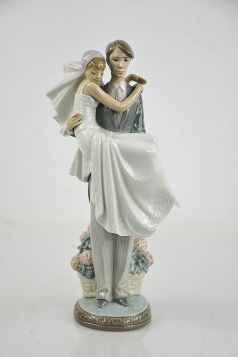 A Lladro porcelain figurine, man carrying bride in his arms.