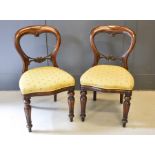 A pair of Victorian balloon back mahogany chairs, with upholstered seats.