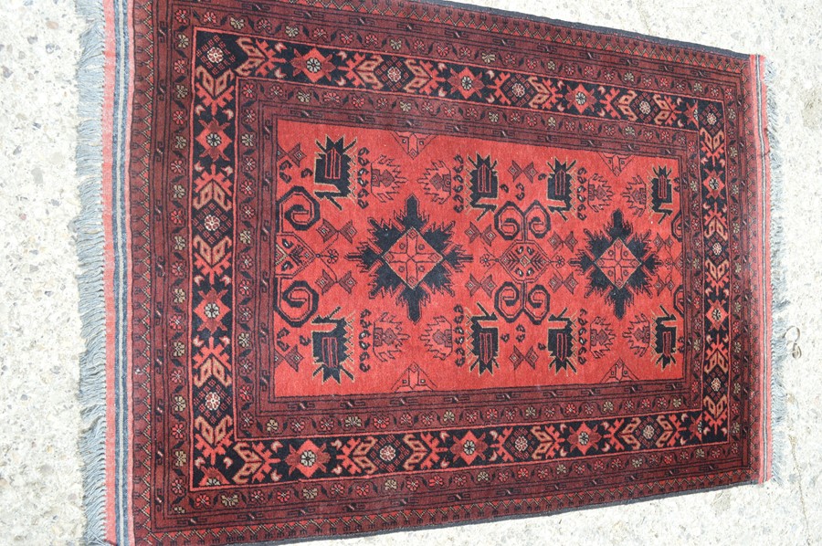 A red ground rug with Aztec design, 105cm by 142cm