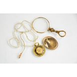 A Victorian gilt metal mourning pendant containing a locket of hair, a gilt metal eye glass, a