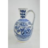 An early 20th century delft blue and white jug of ovid form, embossed with flowers and bird