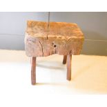 A large antique chopping block raised on splayed stick legs, 54 by 39 by 59cm.