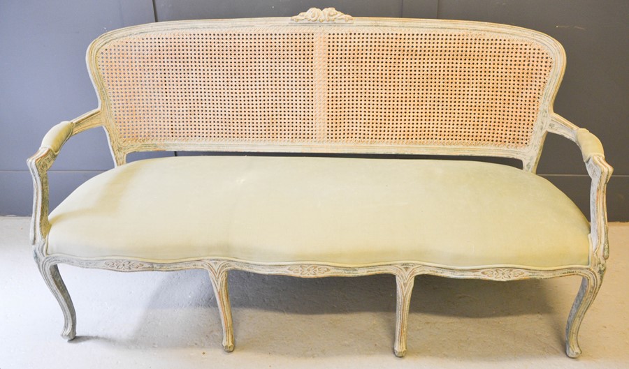 A French 19th century style settee, the caned back with floral carved back, shaped arms and