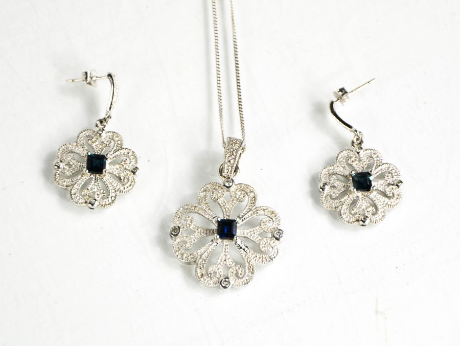 A 9ct white gold, diamond and sapphire pair of earrings and matching necklace, the flower form