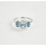 An 18ct gold aquamarine and diamond trilogy ring, J½, 2.65g.