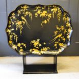 A 19th century Japanese black lacquered tray on stand, the tray decorated with gilded birds of