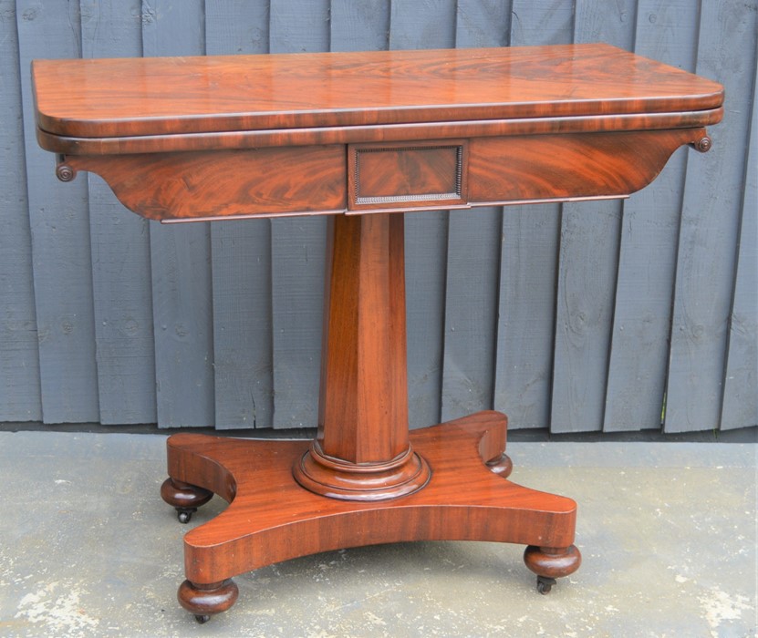A mahogany card table with swivel top, green baize lining and x-form base, 75cm high by 92cm wide by