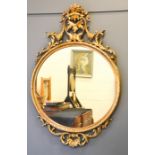 A gilt wall mirror, the circular mirror with crested top, 107cm high.