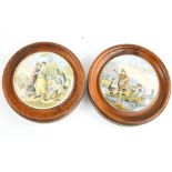 Two Prattware pot lids, in oak roundel frames, depicting figural scenes.