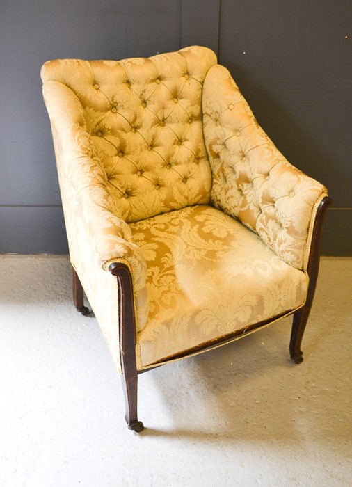 A 19th century button back armchair, upholstered in cream, with a mahogany frame.