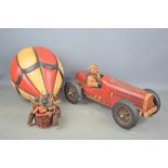 A wooden British race car with steel and rubber wheels together with a composite hot air balloon
