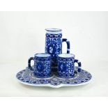 A blue and white pottery mug and jug trio on trefoil stand.