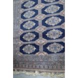 A Middle Eastern blue ground rug with stylised geometric patterns and bearing signature185cm by