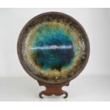 A Studio pottery shallow dish raised on a Chinese style stand, with glass interior. 35cm diameter