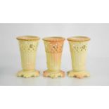 Three Locke & Co Worcester porcelain blush ivory vases, with pierced rims and gilded highlights.12cm