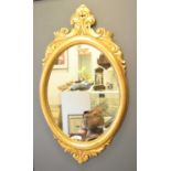 A 19th century style oval giltwood wall mirror with crested scroll work110cm by 62cm