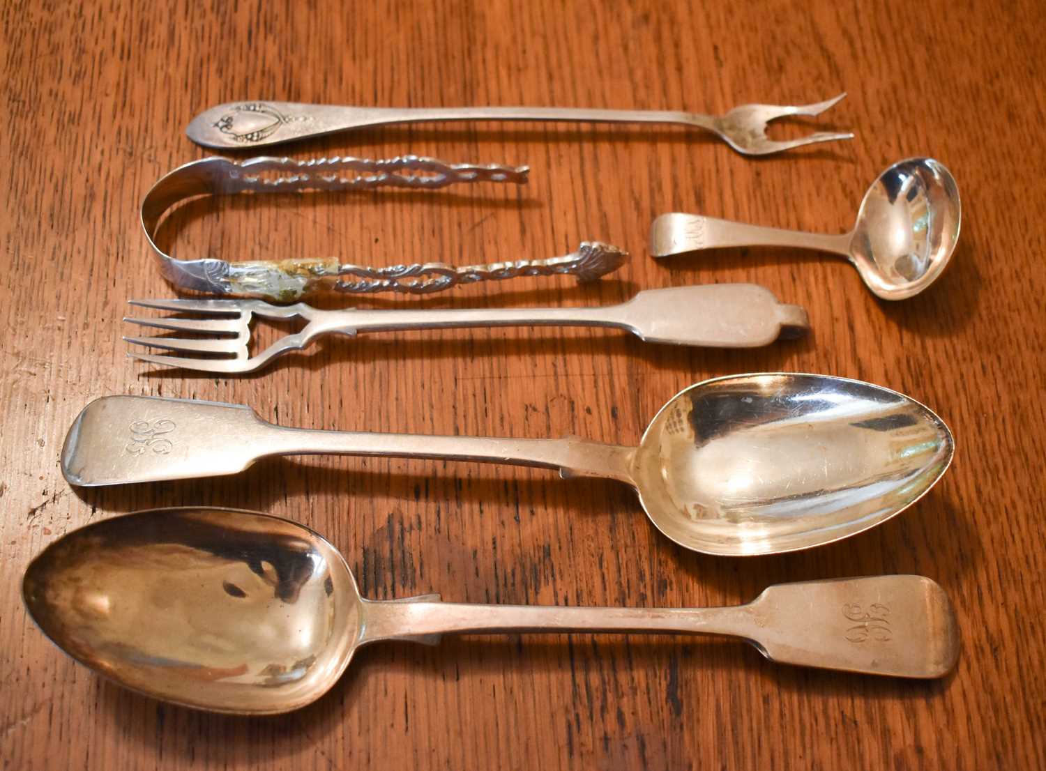 A large silver serving spoon, a Georgian silver baby’s feeding spoon, a fish fork and oyster fork,
