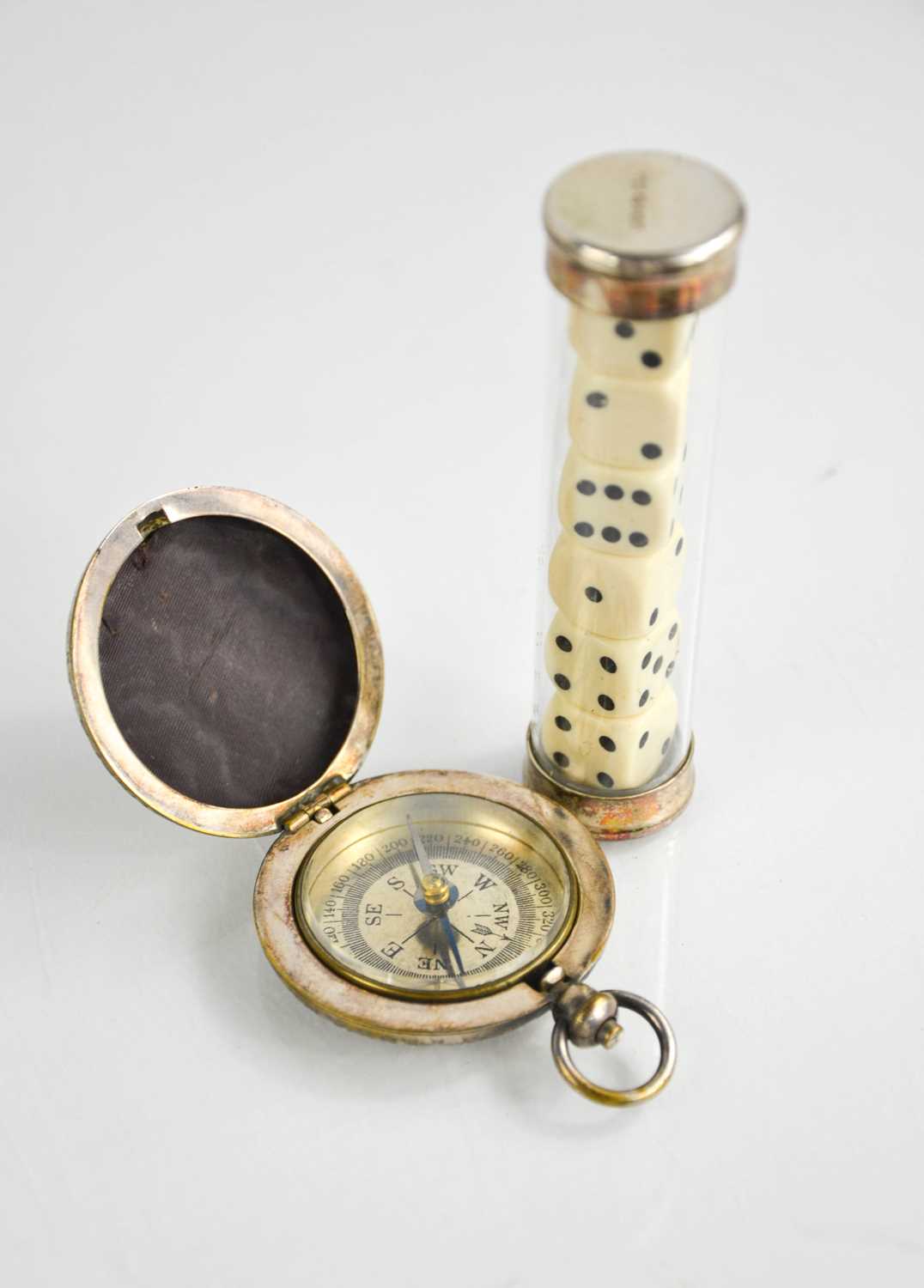 A silver and glass dice holder, containing six die, together with a silver plated embossed compass.