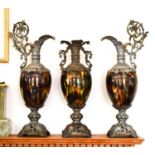 A garniture set of ceramic vase and ewers, treacle glazed ovoid bodies raised on cast metal