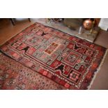 A Turkish wool rug circa 1920 with bold stylised geometric designs and floral borders 206cm by