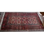 A Middle Eastern wool rug with red ground, stylised motifs to the centre with decorative borders,